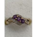 A 9 CARAT GOLD RING WITH DIAMONDS AND PURPLE STONES