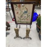 TWO BRASS AND IRON LION FIRE DOGS AND AN EMBROIDERED PEACOCK FIRE SCREEN