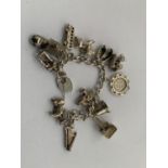A HALLMARKED SILVER CHARM BRACELET WITH TWELVE CHARMS