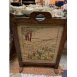 A HAND EMBROIDERED FIRESCREEN ON A WOODEN STAND