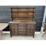 AN ERCOL ELM DRESSER WITH TWO DOORS, FOUR DRAWERS AND UPPER PLATE RACK