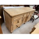 A VICTORIAN PINE KITCHEN DRESSER BASE ENCLOSING SEVEN DRAWERS AND INVERTED CENTRE CUPBOARD, 60" WIDE