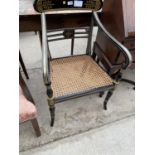 A REGENCY STYLE EBONISED AND GILT ELBOW CHAIR WITH CANE SEAT