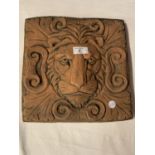 A TERRACOTTA TILE DEPICTING A LION'S FACE