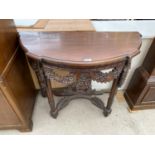 A MAHOGANY DEMI LUNE TABLE WITH HEAVILY CARVED DECORATION