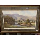 A LARGE PETER SYMONDS FRAMED PICTURE OF A MOUNTAIN RANGE AND RIVER SCENE