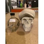 A PEAKY BLINDERS STYLE STONE SKULL AND A GLASS SKULL BOTTLE