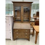 AN OAK BUREAU BOOKCASE WITH FALL FRONT, THREE DRAWERS AND TWO UPPER LEAD GLAZED DOORS
