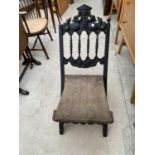 A CARVED AND EBONISED X FRAME FOLDING CHAIR