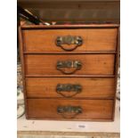 A SMALL WOODEN FOUR DRAWER CHEST OF DRAWERS TO INCLUDE SEWING PARAPHERNALIA