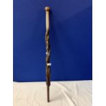 AN INTRICATELY CARVED WOODEN STICK WITH MOTHER OF PEARL STYLE DETAIL AND CROCODILE AND SNAKE DESIGN