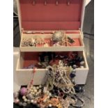 A LARGE CREAM LEATHER EFFECT JEWELLERY BOX CONTAINING A LARGE QUANTITY OF COSTUME JEWELLERY