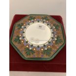 A SMALL CIRCULAR MIRROR WITH A DECORATED CERAMIC SURROUND