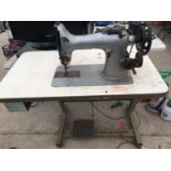 AN INDUSTRAIL SEWING MACHINE WITH WORK TABLE BELIEVD IN WORKING ORDER BUT NO WARRANTY