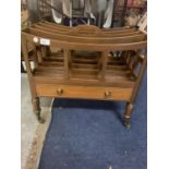 A CANTERBURY MAGAZINE RACK ON CASTORS WITH AN OPENING DRAWER