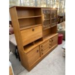 A RETRO TEAK LOUNGE UNIT ENCLOSING SHELVES, GLAZED DOORS, THREE DRAWERS, TWO CUPBOARDS AND A DROP