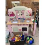 A CHILDRENS WOODEN PLAY KITCHEN WITH PLASTIC PLAY ACCESSORIES