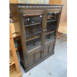 AN ERCOL GLAZED TWO DOOR BOOK CASE WITH CUPBOARD TO THE BASE, 39.5" WIDE, 54.5" HIGH