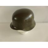 A GREEN PAINTED GERMAN HELMET WITH LEATHER LINER