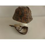 A PLASTIC GERMAN HELMET WITH CAMOUFLAGE COVER AND FOUR LEATHER CHINSTRAPS