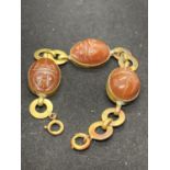 A HEAVY GOLD PLATED BRACELET WITH THREE RED CARVED STONES