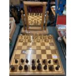 A WOODEN CHESS BOARD WITH MATCHING PIECES AND A FRAMED DRESSING TABLE MIRROR