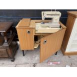 A SINGER ELECTRIC SEWING MACHINE IN A TEAK EFFECT CABINET