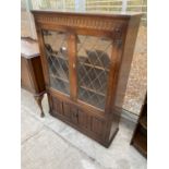 AN OAK PRIORY STYLE GLAZED AND LEADED BOOKCASE WITH LINEN FOLD DOORS TO THE BASE, 38" WIDE