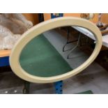 AN OVAL CREAM PAINTED WOODEN FRAMED MIRROR