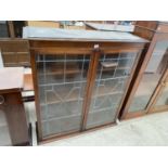 AN EDWARDIAN MAHOGANY TWO DOOR BOOKCASE WITH GLAZED AND LEADED DOORS, 44" WIDE