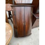 A GEORGE III OAK BOWFRONTED CORNER CUPBOARD WITH SHAPED INTERIOR SHELVES