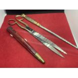 A DESK SET TO INCLUDE A LETTER OPENER AND SCISSORS WITH ORNATE WHITE METAL HANDLES AND A RED LEATHER