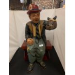 A LARGE RESIN CHARACTER ORNAMENT FEATURING A VENTRILOQUIST IN A BOWLER HAT SEATED ON A WOODEN BENCH