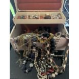 A LARGE CREAM LEATHER EFFECT JEWELLERY BOX CONTAINING A LARGE QUANTITY OF COSTUME JEWELLERY