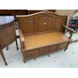 AN OAK SETTLE WITH THREE SECTION PANELED BACK AND HINGED SEAT