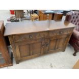 AN OAK SIDEBOARD WITH TWO DOORS AND TWO CARVED PANEL DRAWERS