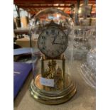 A GERMAN KUNDO ANNIVERSARY CLOCK WITH ORNATE FACE, KEY AND GLASS DOME