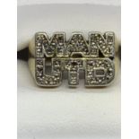 A SILVER AND GOLD PLATED MANCHESTER UNITED RING WITH CLEAR STONE CHIPS