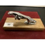 A CHROME JAGUAR MASCOT ON A WOODEN PLINTH