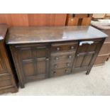 AN ERCOL ELM SIDEBOARD WITH TWO DOORS AND FOUR DRAWERS