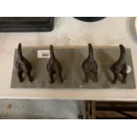 A SET OF CAST IRON DOG COAT HOOKS ON A SLATE BACKING