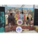 A VERY LARGE PRINT OD THE BEATLES SERGEANT PEPPER'S ALBUM COVER WITH THREE FACE CUT OUTS