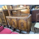 AN OAK SIDEBOARD ON PINEAPPLE BALUSTER SUPPORTS WITH THREE DOORS