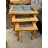 A BEECH NEST OF TABLES WITH GLASS TOPS