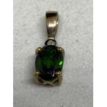 A 9 CARAT GOLD PENDANT WITH A GREEN STONE AND A CLEAR STONE