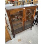 AN OAK BOOKCASE CABINET ON CABRIOLE SUPPORTS WITH TWO LEADED AND STAINED GLASS DOORS