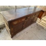 A GEORGE III OAK DRESSER BASE ENCLOSING THREE FRIEZE DRAWERS, THREE PANELLED CUPBOARDS, ON BRACKET