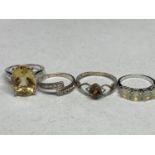 FOUR ASSORTED SILVER RINGS TO INCLUDE A LARGE YELLOW STONE, AN AMBER STYLE STONE, CLEAR STONE AND