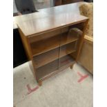 A SMALL TEAK BOOKCASE WITH TWO SLIDING GLASS DOORS