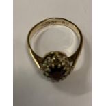 A 9 CARAT GOLD DRESS RING WITH RED AND CLEAR STONES (ONE STONE MISSING)